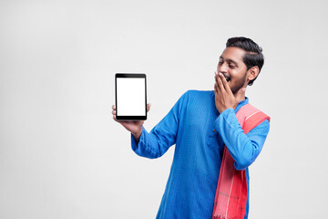 Wall Mural - Young indian farmer showing tablet and giving expression on white background.