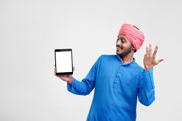 Wall Mural - Young indian farmer showing tablet and giving expression on white background.