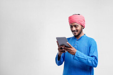 Wall Mural - Young indian farmer using tablet and giving expression on white background.