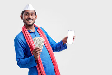 Wall Mural - Young indian farmer showing smartphone and money on white background.