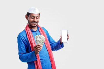 Wall Mural - Young indian farmer showing smartphone and money on white background.