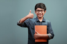 Smiling Boy Holding Note Books In Hands Shows A Thumbs Up Gesture