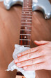 © Maria Shchipakina - Guitar master polishing fretboard of electric guitar with cloth