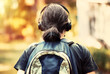 © Cagkan - Facing back teenager high school boy with headphones and backpack walks towards the school building.