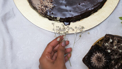 Sticker - Overhead shot of a female hand with a small flower and chocolate desserts on the table