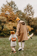 © Ananass - Young happy and smiling mom with her little daughter in arms hugging and kissing spending a weekend on a walk in autumn park. selective focus, noise effect, Autumnal mood