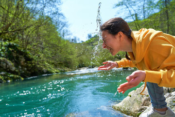 The girl washes herself with crystal clear water from a mountain river. Hiking in the mountains