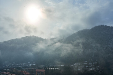 Wall Mural - Winter mountain landscape. Small town between mountains. A cloud hangs over the city