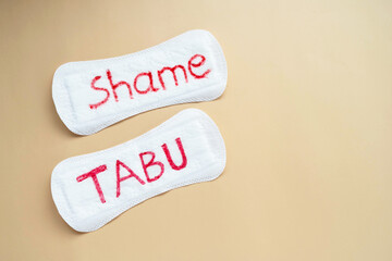 Woman's sanitary pad with word tabu and shame. Abstract social concept of shaming women for their menstruation