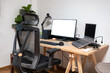 © Mumemories - Wooden desk with laptop, display, mouse, lamp, ergonomic chair and artificial tree in workplace on bedroom