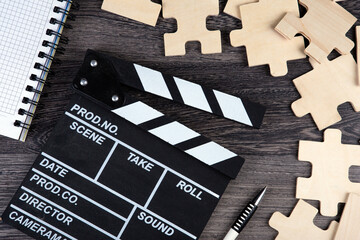 Wall Mural - cinematic  clapper with notepad, pen and puzzle pieces on a table