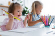 © LIGHTFIELD STUDIOS - happy toddler kid with down syndrome holding pencils near blurred blonde girl