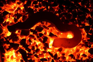 Poster - The bright background consists of a burning anthracite coal and a steel object glowing on it.