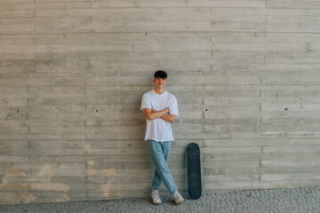 Canvas Print - teen boy with skateboard on wall with copy space