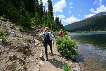 Wall Mural - Two young female hikers on shore of Upper Urad Reservoir on Hassell Lake Trail in Arapaho National Forest, Colorado on sunny summer afternoon.