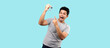 happy Asian man, guy holding a car key and pointing to it,on blue background in studio With copy space.