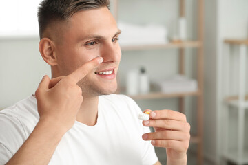 Wall Mural - Young man putting in contact lenses at home