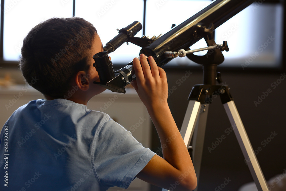 Little boy with telescope looking at stars in evening