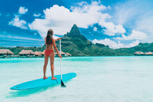 SUP Tahiti Paddleboard Woman Standing On Stand-up Board Paddling Over Turquoise Ocean At Luxury Beach Resort Hotel On Bora Bora Island, French Polynesia.