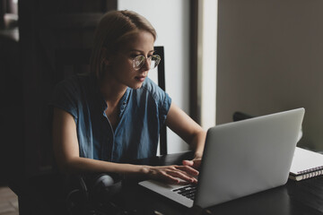 Woman with blond hair working or learning via laptop computer at home