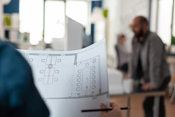Poster - Architects looking at plans of blueprints for design of building model sketch layout maquette. Professional adult team working on architectural construction drawing as job occupation