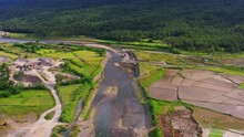Shallow Stream Flowing By The Farmland With Quarry Crushed Stone Area During Summer. - Aerial