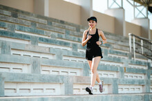 Middle-aged Beautiful Sport Asian Woman Outdoor Runner Athlete Running On Stadium Stairs Active And Healthy Lifestyle.