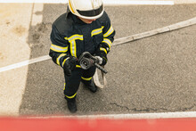 One Young Male Firefighter Dressed In Uniform With Water Hose Ready For Deployment