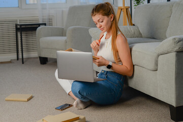 Wall Mural - beautiful young woman with laptop at home on the couch. chatting online, lifestyle