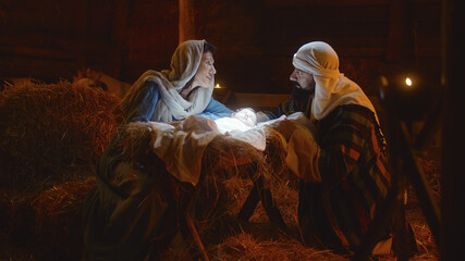 Mary and Joseph caressing baby Jesus in illuminated manger