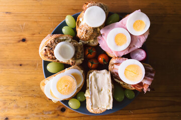 Wall Mural - Top view of a natural dish food with boiled eggs, tomatoes, cheese sandwiches on a brown table