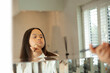 © Anna Neubauer - Young biracial woman with Down Syndrome applying make-up with brush in the bathroom