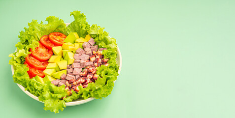 Wall Mural - Green lettuce salad with fresh mixed purple corn, purple yams, avocado, and tomatoes on a dish isolated on a green background. Space for text. Concept of healthy foods and vegetables