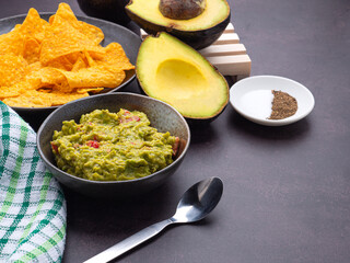 Wall Mural - Fresh guacamole on a dish with ingredients for homemade guacamole avocados, lemon, salt, and pepper placed on the old kitchen table. Side view. Concept of traditional Mexican foods