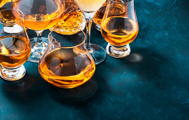 Wall Mural - Strong alcohol drinks, hard liquors, spirits and distillates iset in glasses: cognac, scotch, whiskey and other. Blue background, top view
