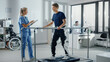 © Gorodenkoff - Modern Hospital Physical Therapy: Doctor Uses Tablet Computer, Helps Disabled Patient with Injury Walk on Treadmill Wearing Advanced Robotic Exoskeleton Legs. Physiotherapy Rehabilitation Technology