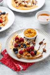 Wall Mural - Close up of crepes with berries and jam on plate, breakfast