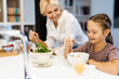 © Drobot Dean - White mother and daughter smiling while having lunch in kitchen at home