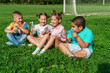 Small children, preschoolers drink water sitting on grass in park on sunny summer day. Outdoor games in fresh air. fun childhood. An active game. Water balance. children are very thirsty.