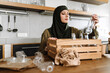 © Drobot Dean - Smiling islamic woman in hijab sorting glass bottle