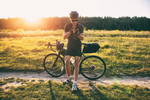 The bike traveler got lost in the middle of field and looking for the route in the smartphone