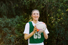 Horizontal Shot Of A Young Smiling Woman In Sports Wear Holding A Net Ball With Two Hands