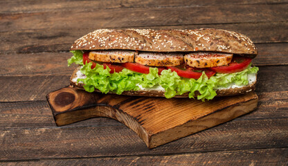 Heathy sandwich with chicken and vegetables on rustic wooden background.