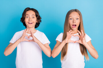 Canvas Print - Photo portrait boy girl excited showing paper heart sign fingers isolated pastel blue color background