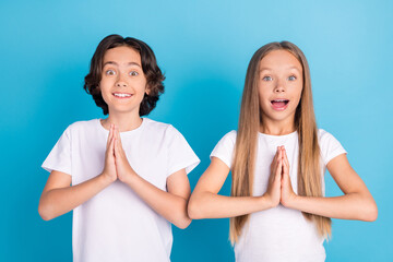 Canvas Print - Photo of two cheerful children hold hands plead excited mood wear white t-shirt isolated blue color background