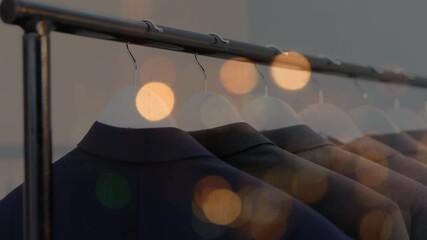 Poster - Animation of bokeh lights over jackets hanging on display in clothes shop