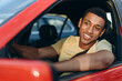 © speed300 - Horizontal view of the young multiracial man smiling while sitting at the car at the driver place and driving car at the traffic jam. Road trip concept
