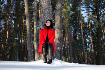 a series of photographs with a young woman in the winter forest. girl in a snowy park. in a red jacket. winter walk in nature. Cold season.