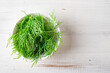 Fresh dill on a plate on a white wooden background. Cooking ingredient.
