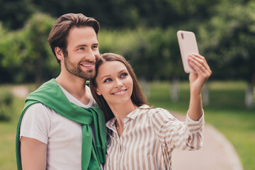 Poster - Photo of young attractive couple happy positive smile boyfriend girlfriend hug make selfie cellphone outdoors